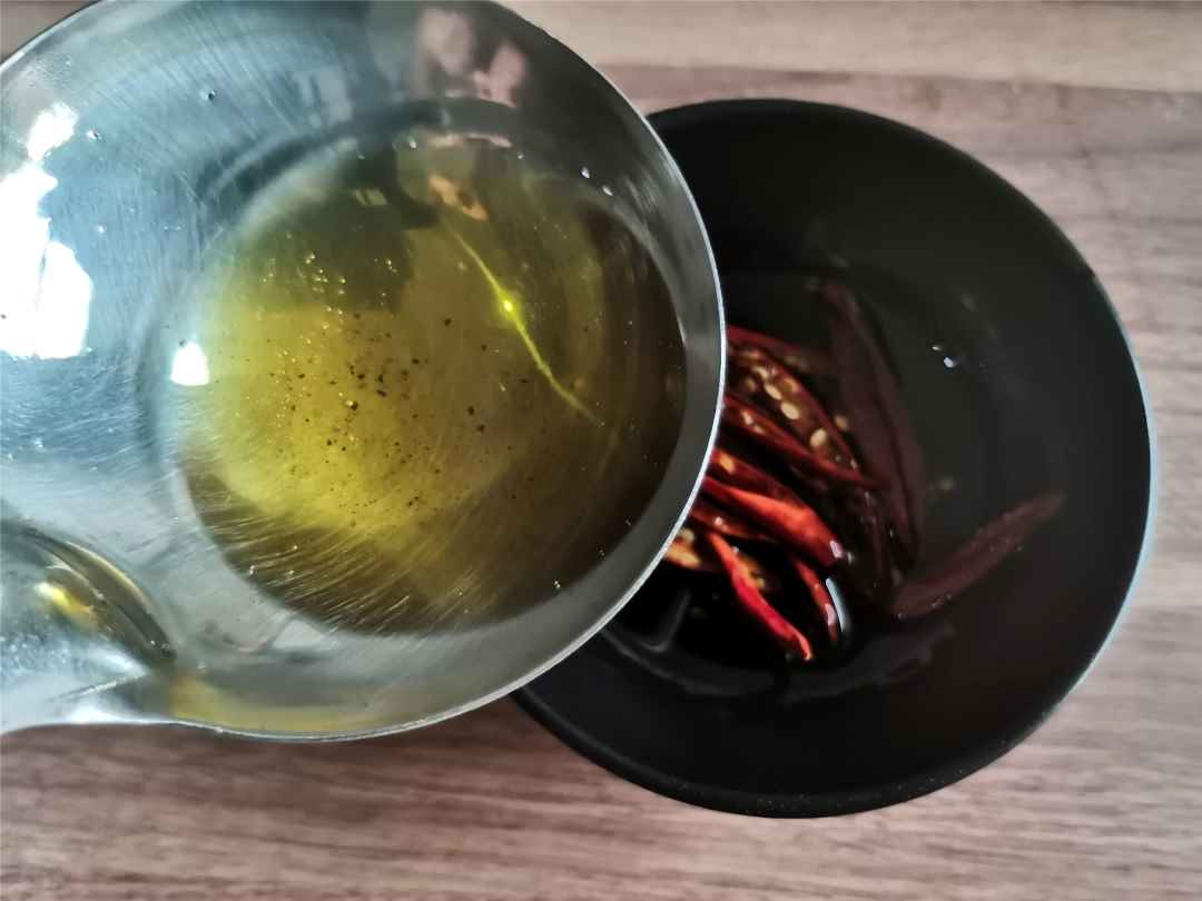 Pour the hot pepper oil into the bowl with dried chili peppers