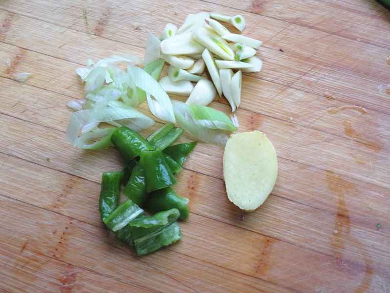Cut green peppers into pieces, chop green onions, and slice ginger and garlic